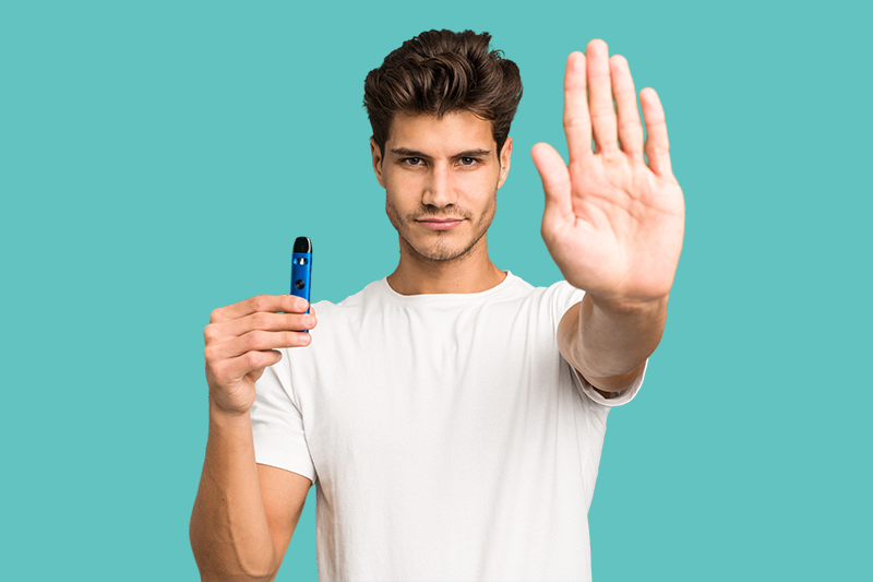 Gli effetti della sigaretta elettronica sulla salute orale sono mostrati da un ragazzo che fa il segno di stop con una mano e ha la sigaretta elettronica nell'altra